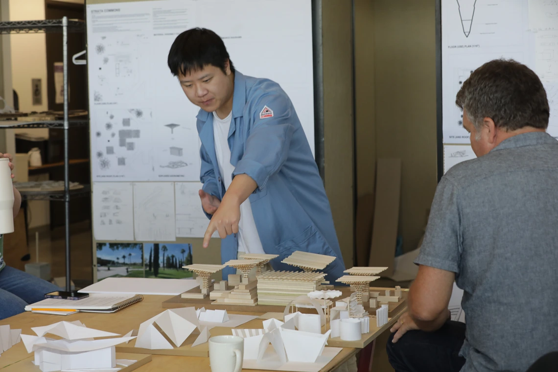 M.Arch student points at his model.